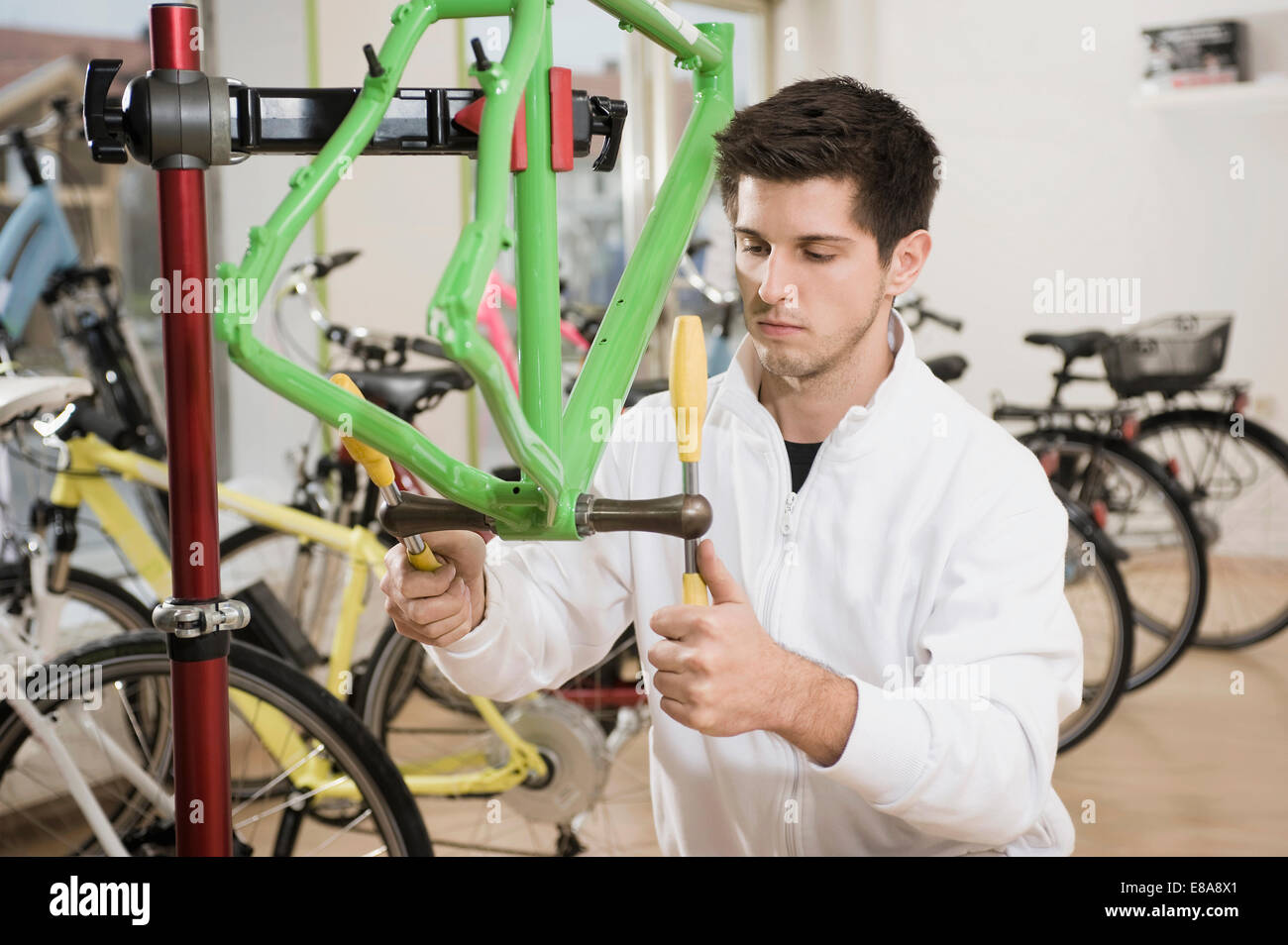 Junger Mann arbeitet an Fahrradrahmen Stockfoto