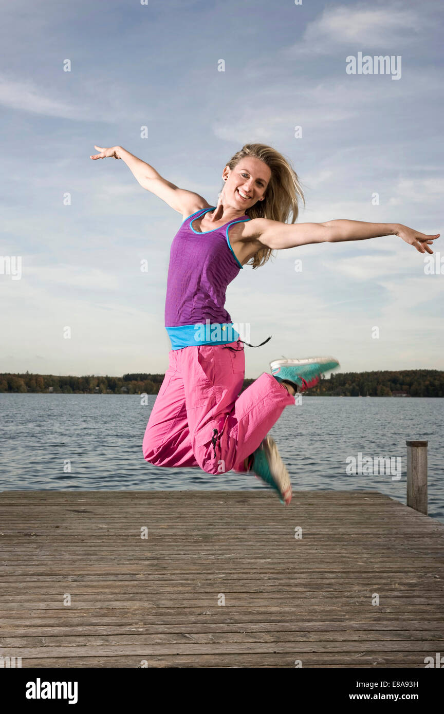 Frau tanzt Zumba auf Steg, Woerthsee, Bayern, Deutschland Stockfoto