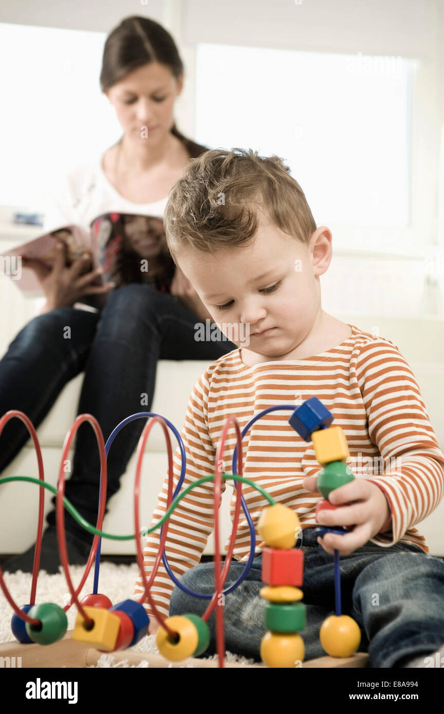 Jungen spielen während Mutter auf sofa Stockfoto