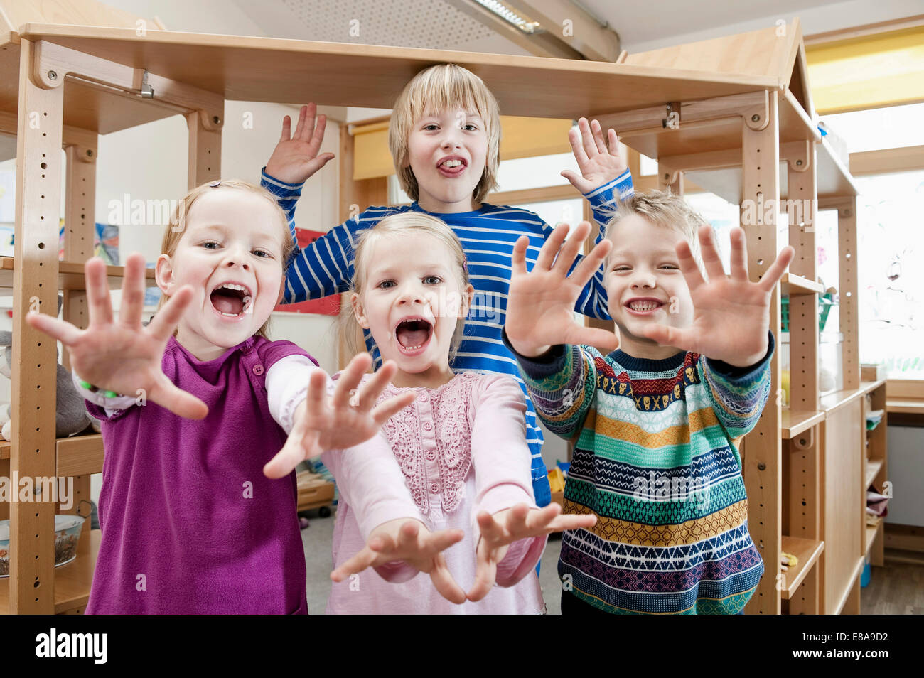 Vier Kinder mit ausgestreckten Armen schreiend Stockfoto