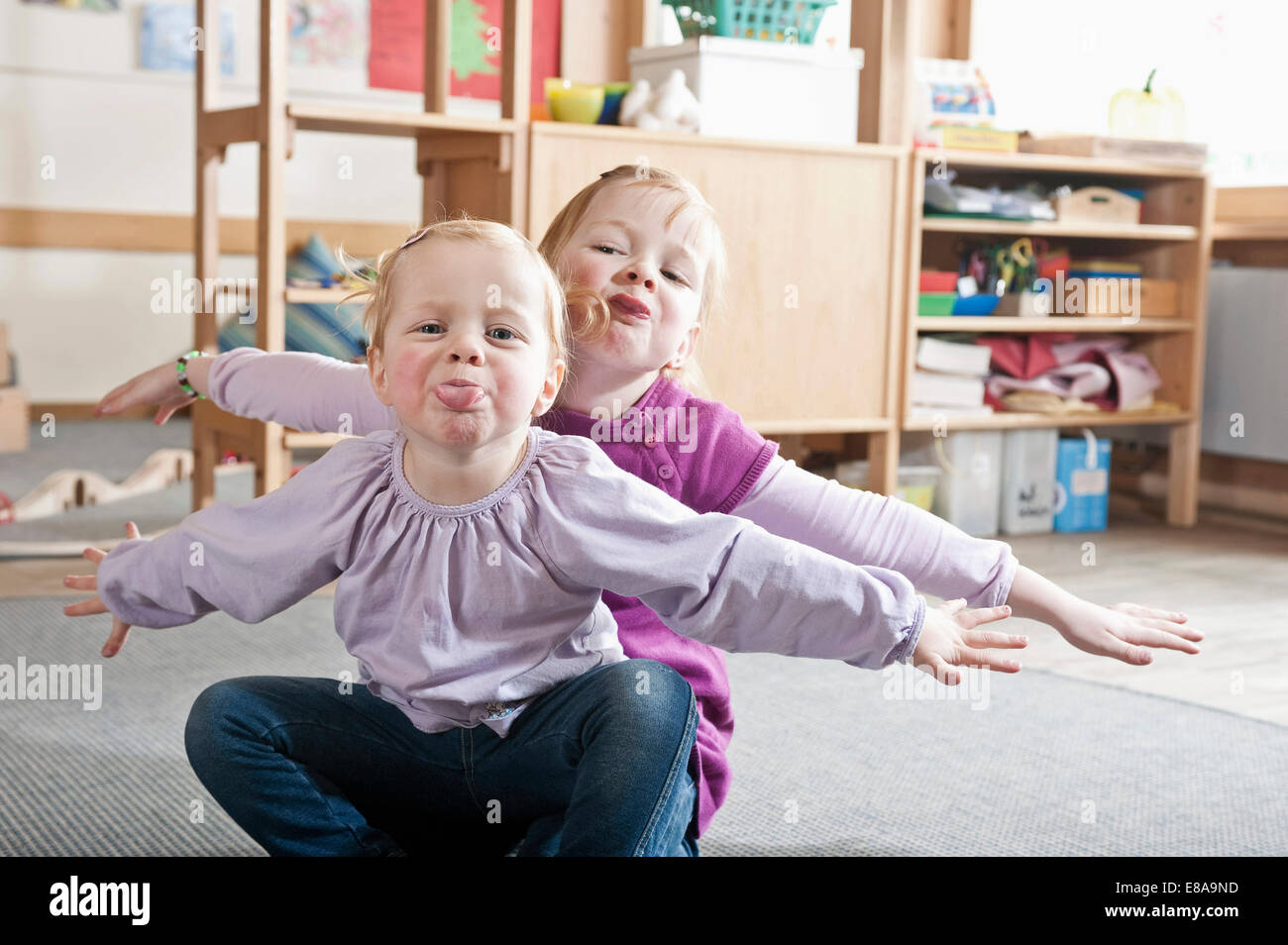 Porträt von zwei kleine Schwestern im Kindergarten Zungen herausragen Stockfoto