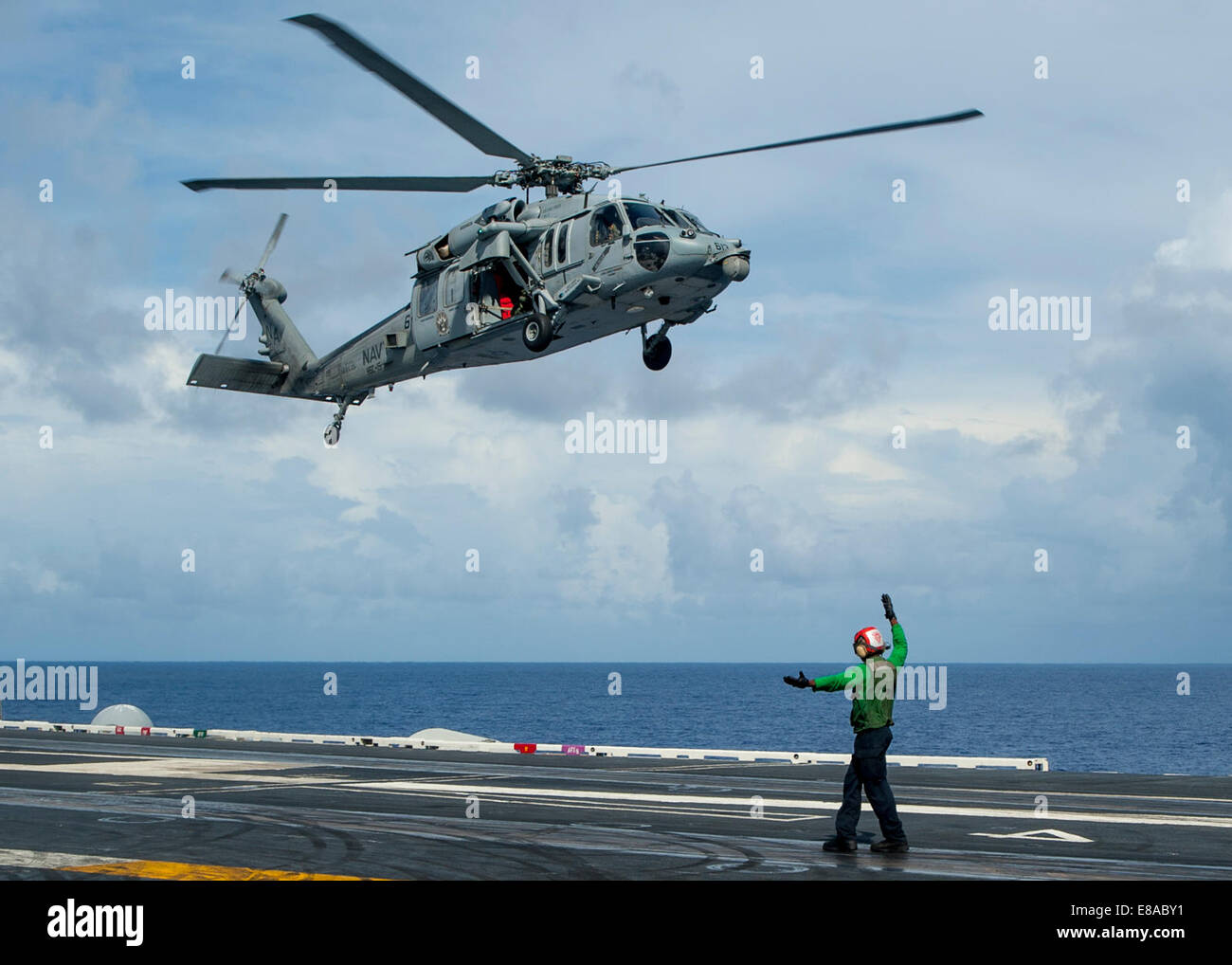 US Marine Aviation Maschinist? s Matt 3. Klasse Alex Lasan Signale die Piloten eines MH-60 Seahawk-Hubschrauber, Hubschrauber Meer bekämpfen Squadron (HSC) 15, 22. September 2014, landen auf dem Flugdeck des Flugzeugträgers USS Carl Vinson (CVN-70) zugewiesen in Stockfoto