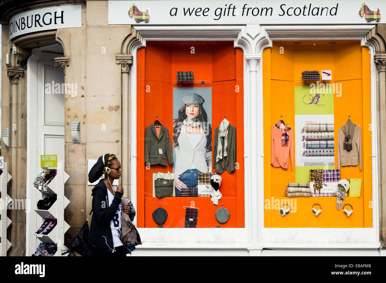 Frau mit Kopfhörern zu Fuß vorbei an einen schottischen Geschenkeladen auf der Royal Mile, Altstadt von Edinburgh, Schottland Stockfoto