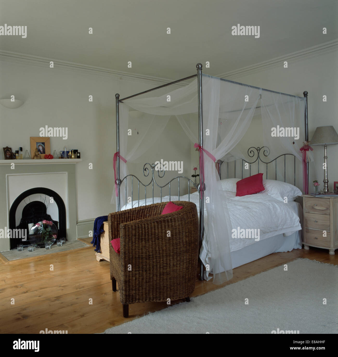 Wanne Korbstuhl neben Chrom Himmelbett mit weißen Voile Vorhänge und weißen  Bettdecke in weißen Land Schlafzimmer Stockfotografie - Alamy