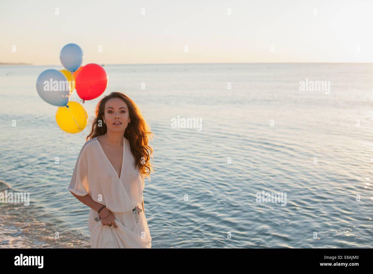 Porträt der jungen Frau am Strand mit Luftballons, Castiadas, Sardinien, Italien Stockfoto