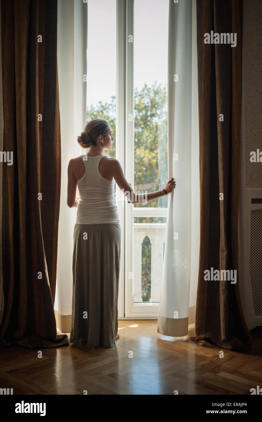 Elegante junge Frau aus dem Wohnzimmer Fenster suchen Stockfoto