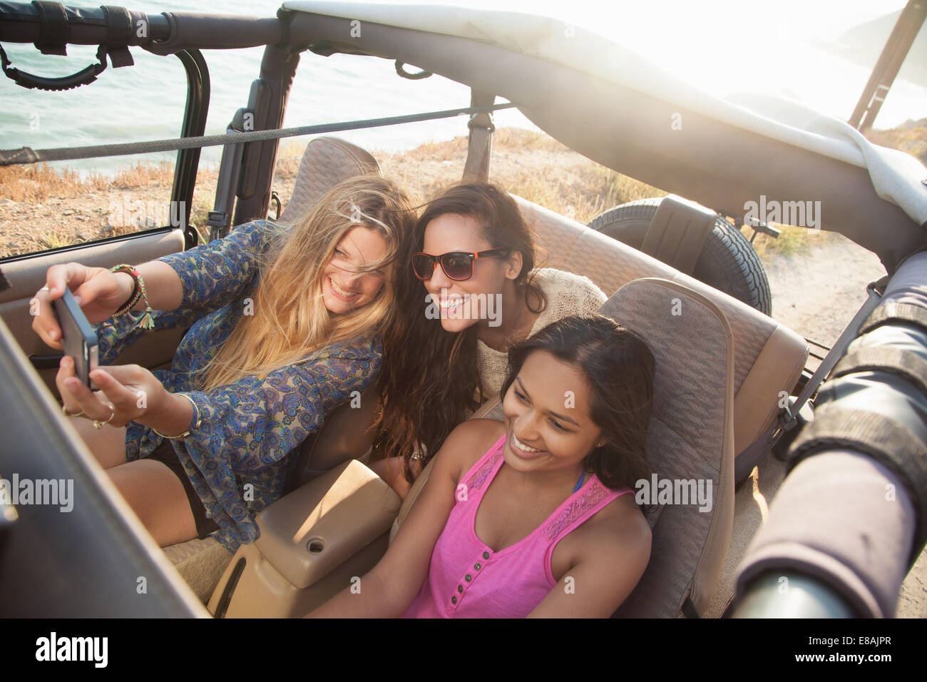 Drei junge Frauen, die die Selfie auf Smartphone im Jeep an Küste, Malibu, Kalifornien, USA Stockfoto
