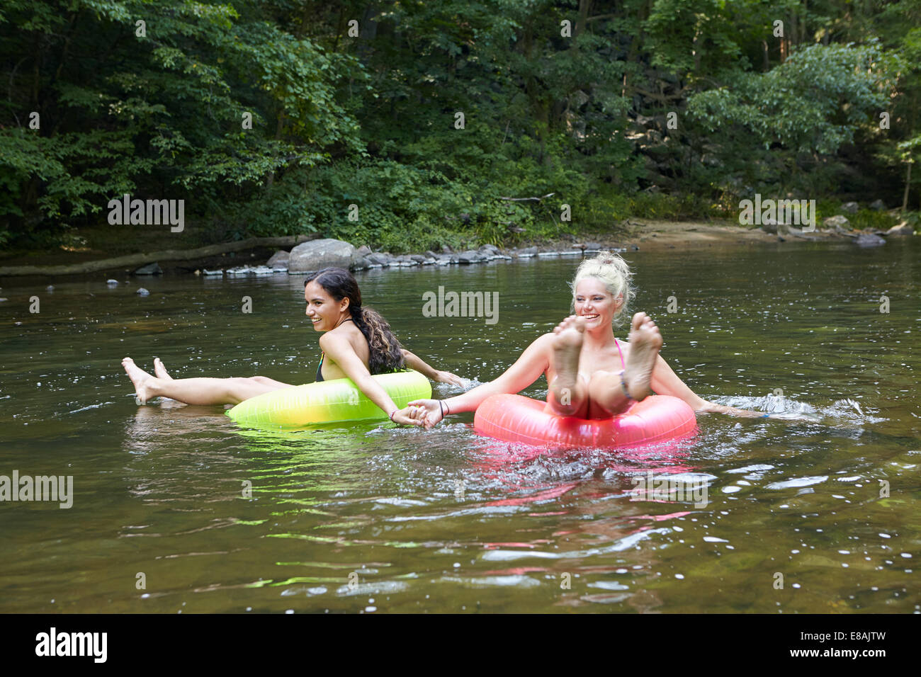 Frauen im Fluss mit aufblasbaren Ringen Stockfoto