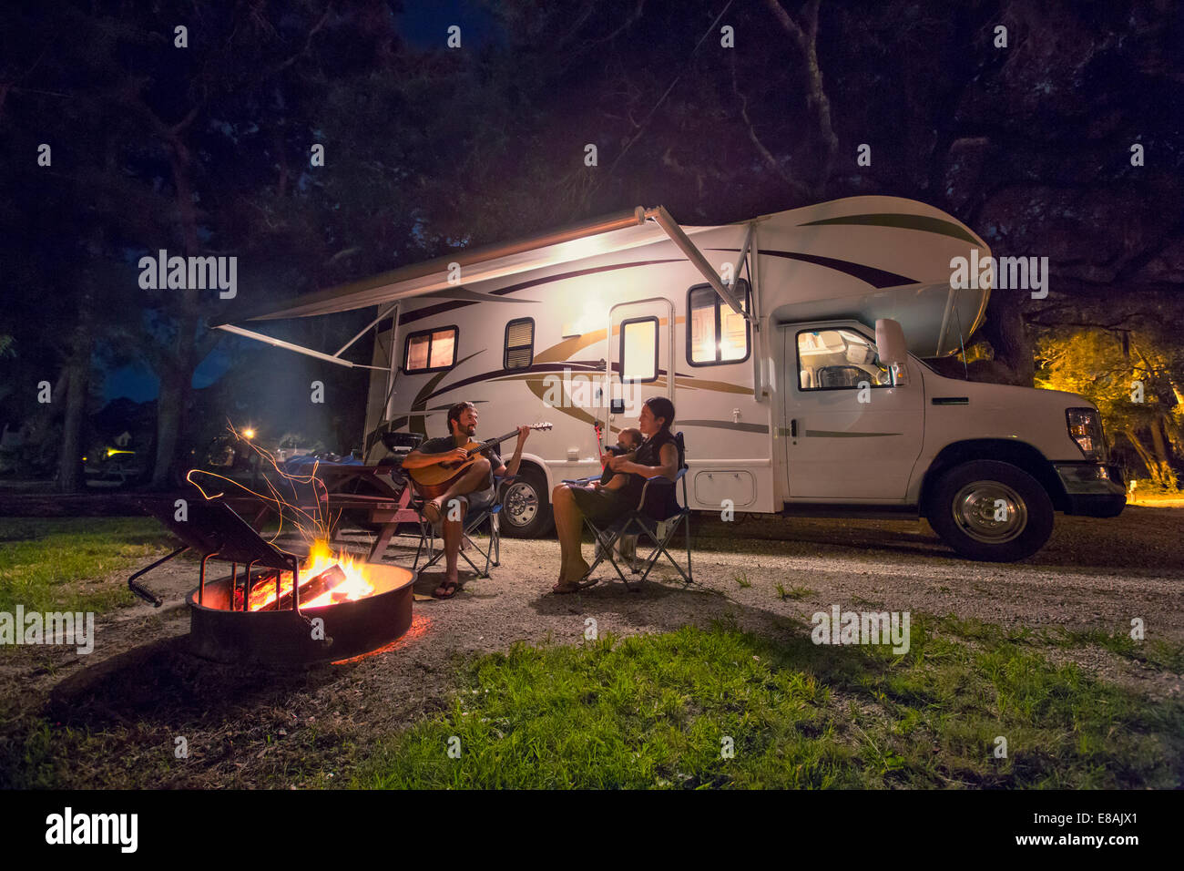 Mitte erwachsenes paar und Tochter sitzen vor am Lagerfeuer in der Nacht Stockfoto