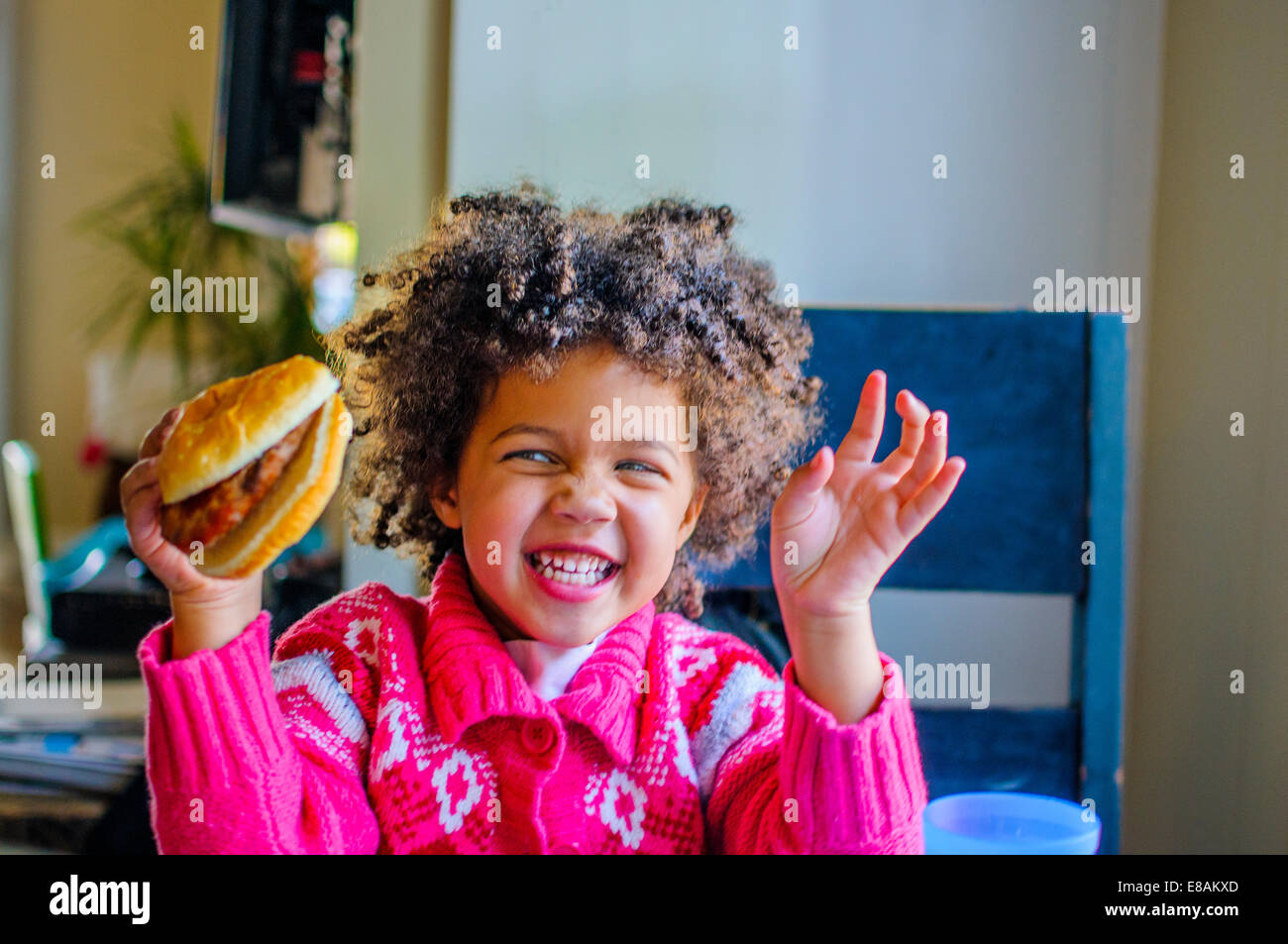 Niedliche Mädchen Lachen und hält Hamburger Küche Stockfoto