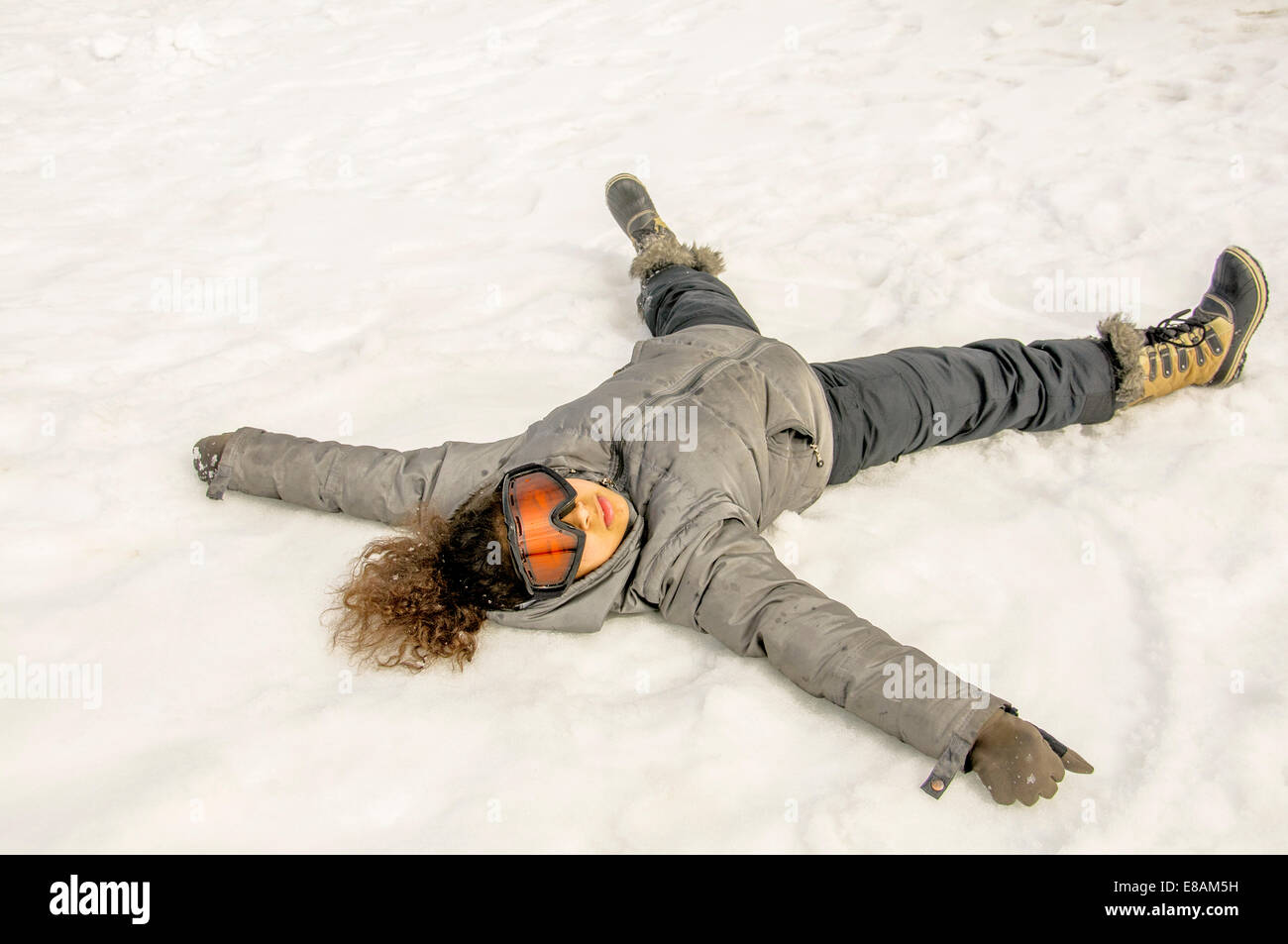 Mädchen auf dem Rücken im Schnee liegend Stockfoto