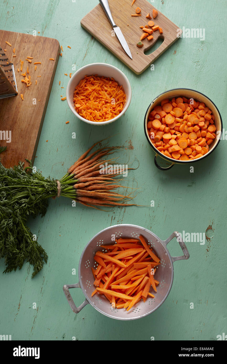 Gehackt, in Scheiben geschnitten, geraspelt und Bund Karotten auf Küchentisch Stockfoto