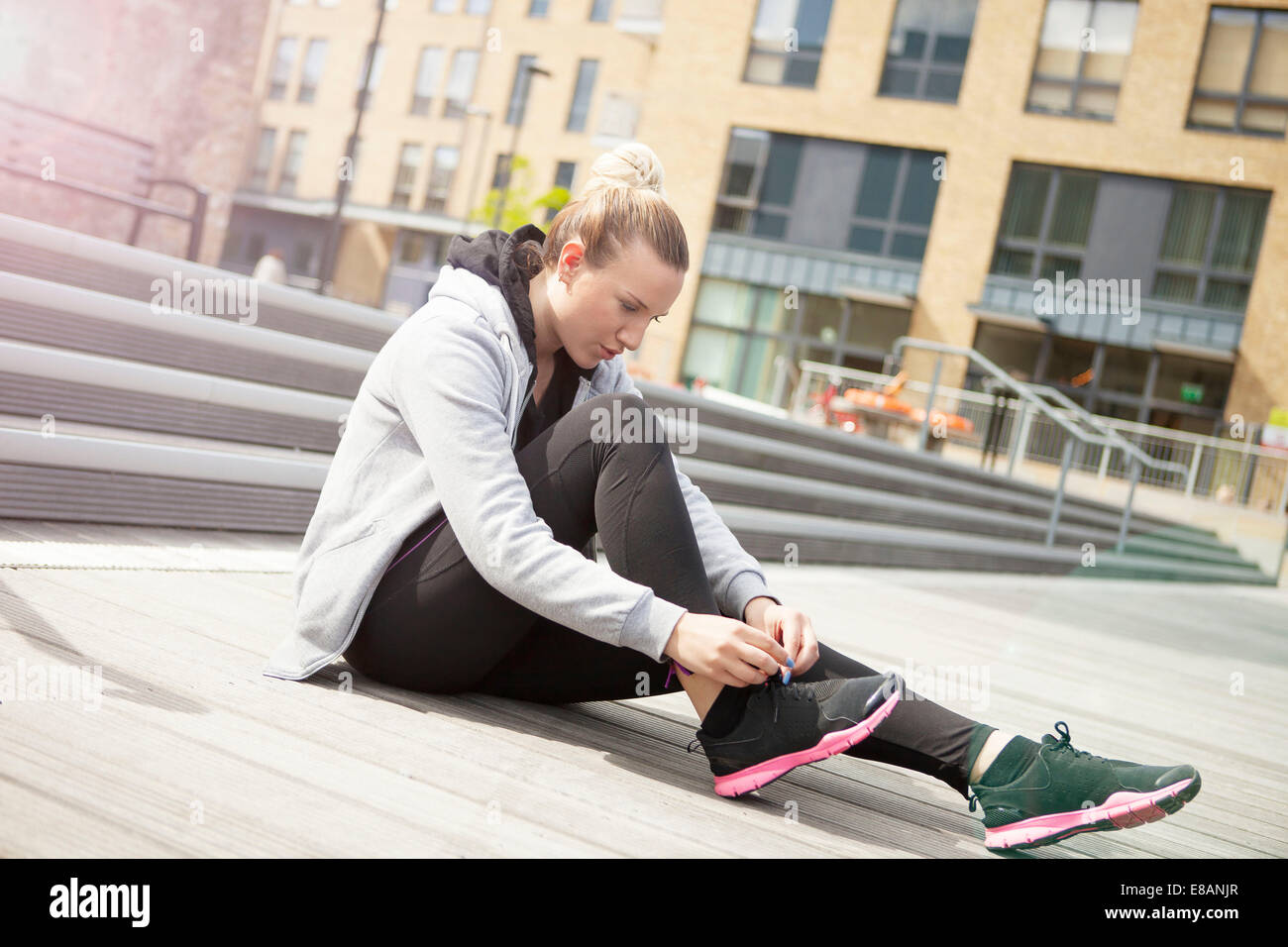 Frau sitzt am Boden, die Schnürsenkel zu binden Stockfoto