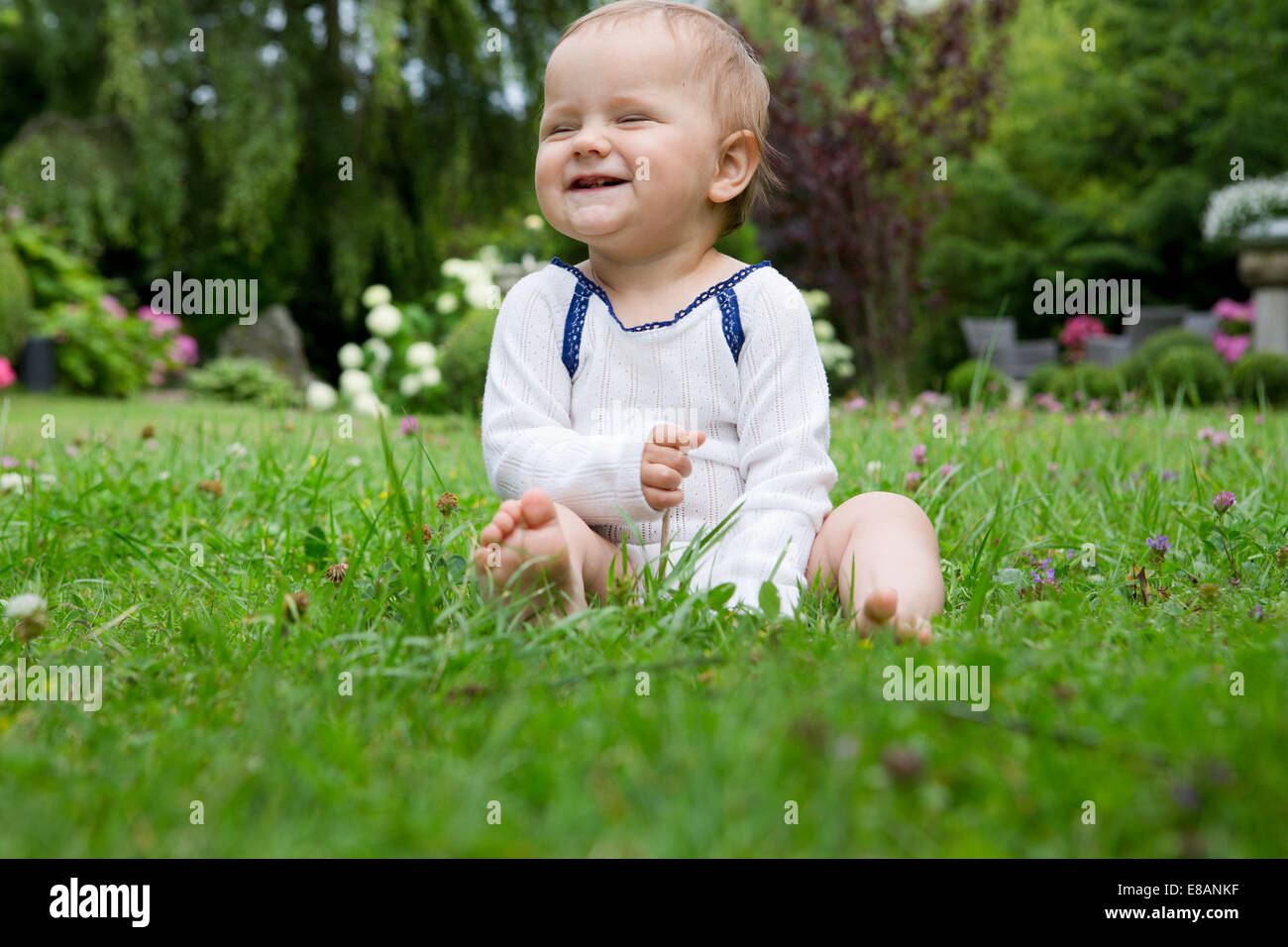 Porträt von Babymädchen sitzen auf Rasen vor Lachen Stockfoto