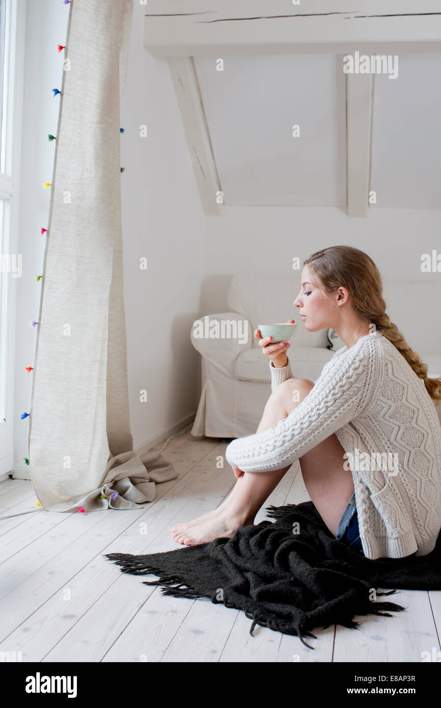 Frau sitzt auf Etage Tee trinken Stockfoto