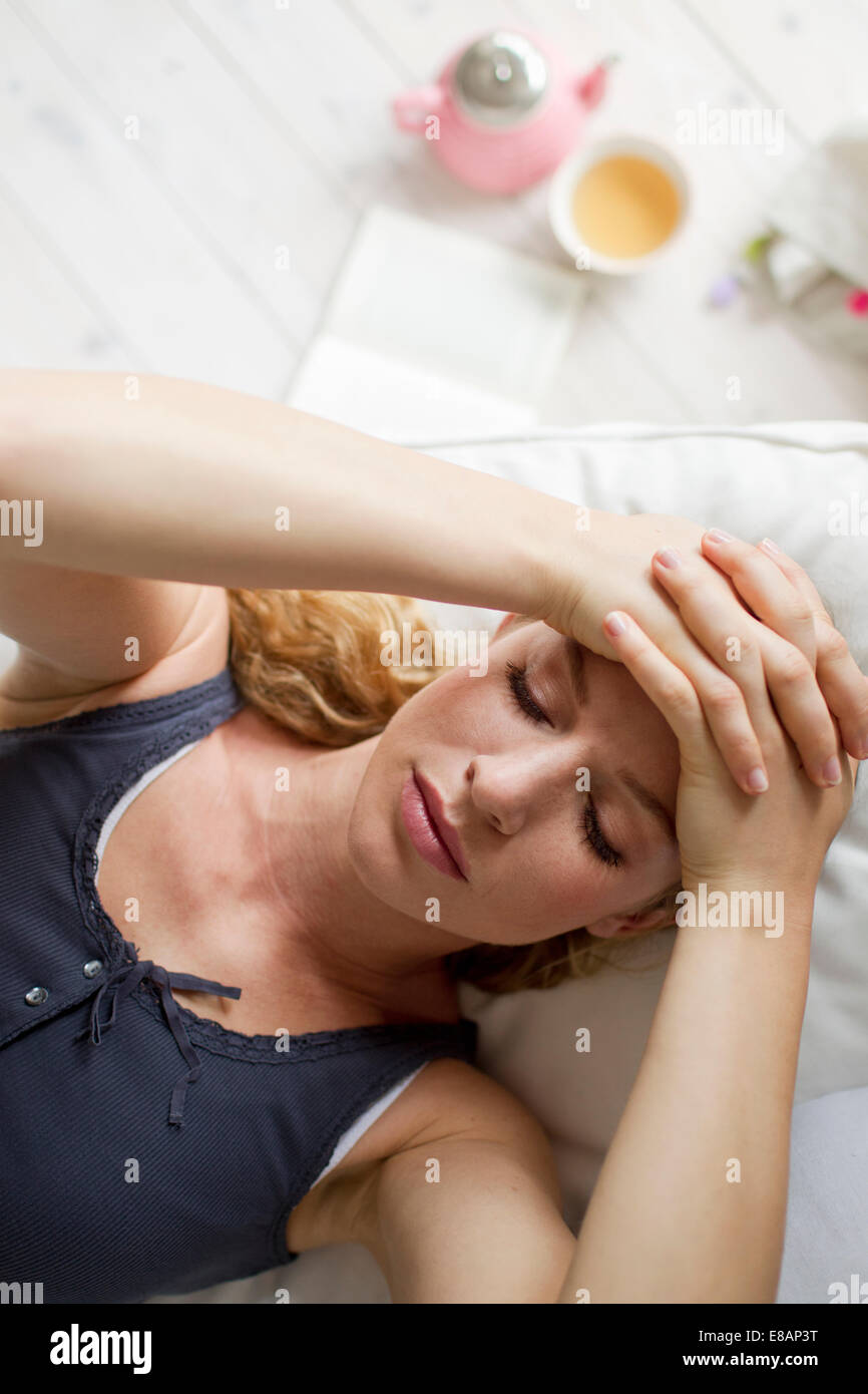 Frau liegend auf Sofa mit Händen auf Kopf Stockfoto