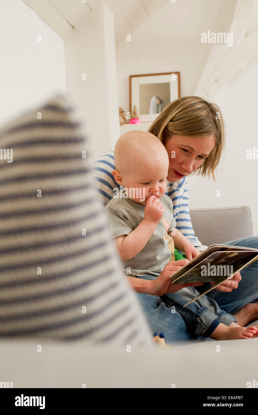 Reife Mutter und Baby Tochter Lesung Märchenbuch auf Wohnzimmer-sofa Stockfoto
