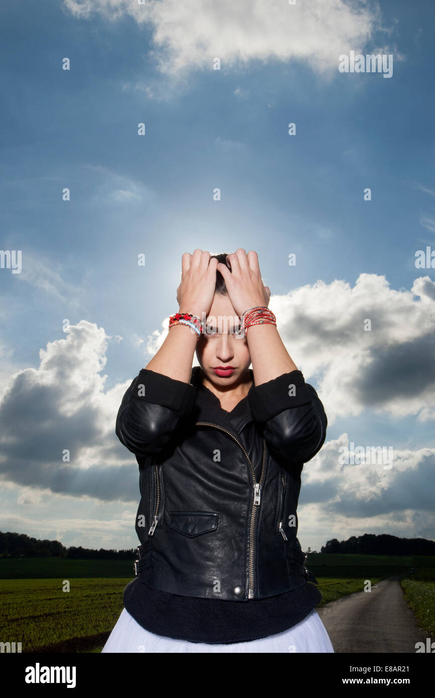 Porträt der jungen Frau auf Landstraße mit Kopf in Händen Stockfoto
