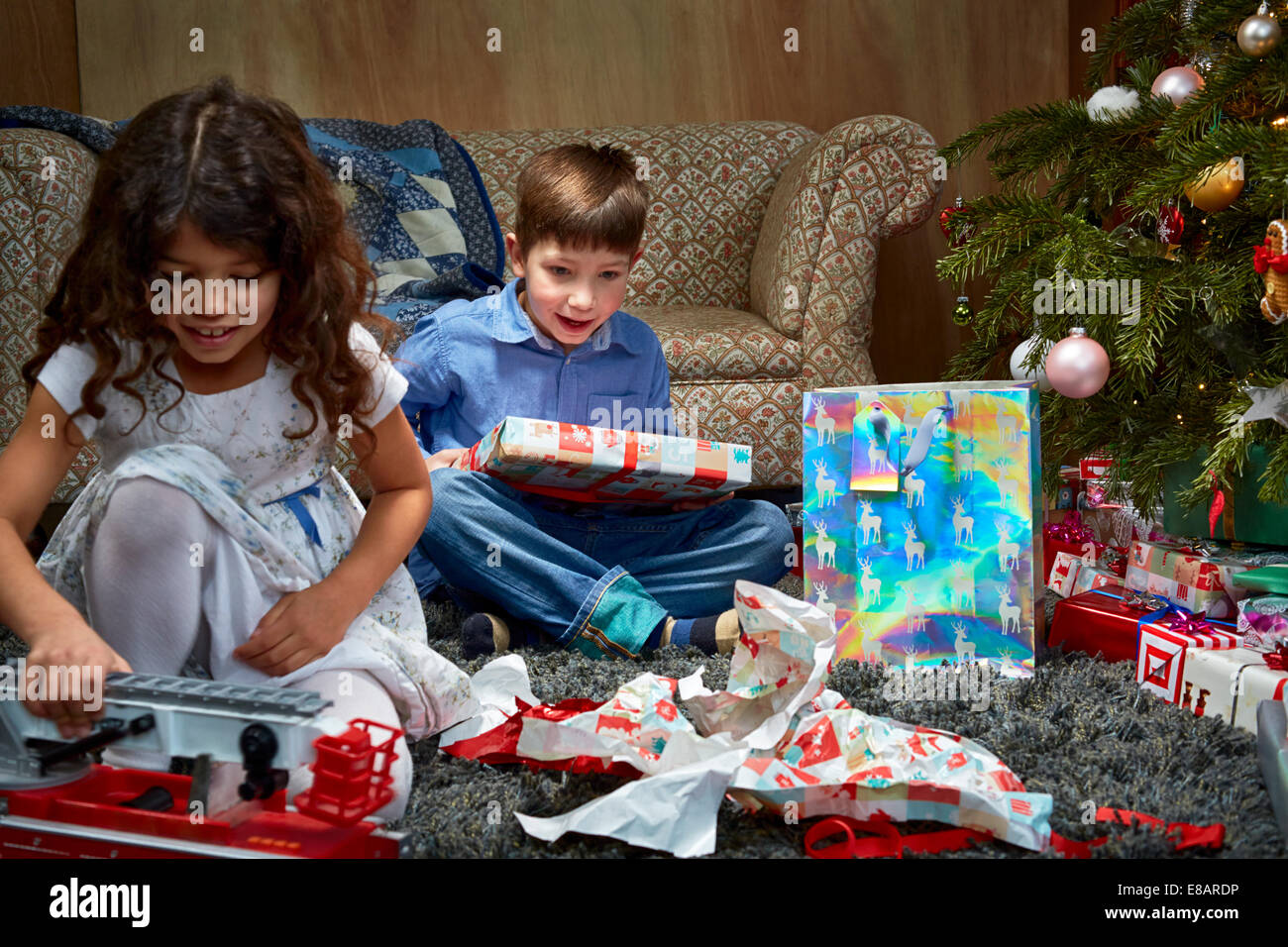 Schwester und Bruder im Wohnzimmer Auspacken und spielen mit Weihnachtsgeschenke Stockfoto