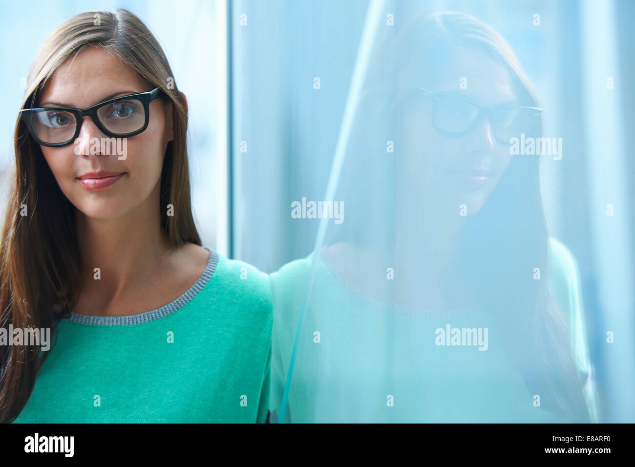 Porträt von Mitte adult Geschäftsfrau gelehnt Glaswand im Büro Stockfoto