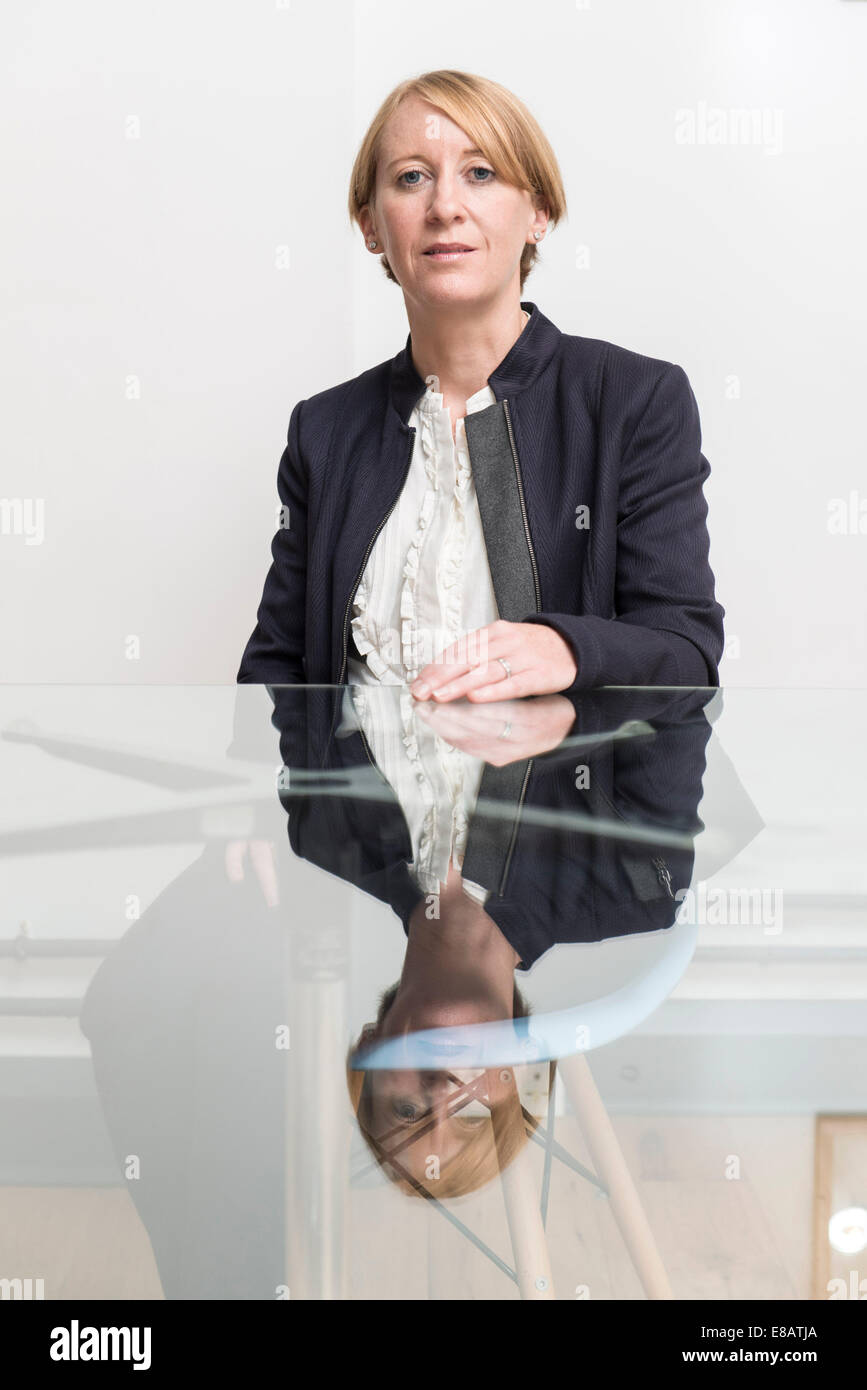 Eine kurzen Haaren Business-Frau sitzt am Tisch aus Glas in einem Konferenzraum in einem Business-Anzug, ernst Stockfoto