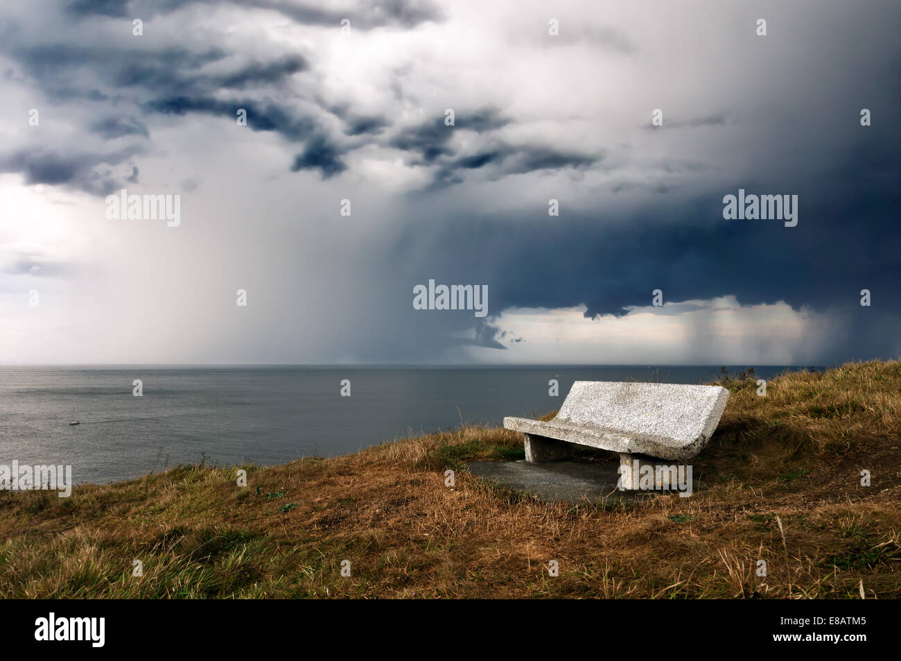 Bank auf Klippe mit Sturm über dem Meer Stockfoto