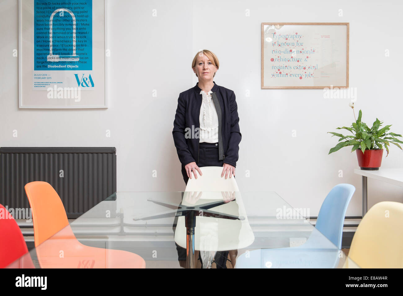 Eine kurze Haaren Geschäftsfrau im Anzug sitzt in einem kühlen Büros Tagungsraum mit farbigen Stühle Stockfoto
