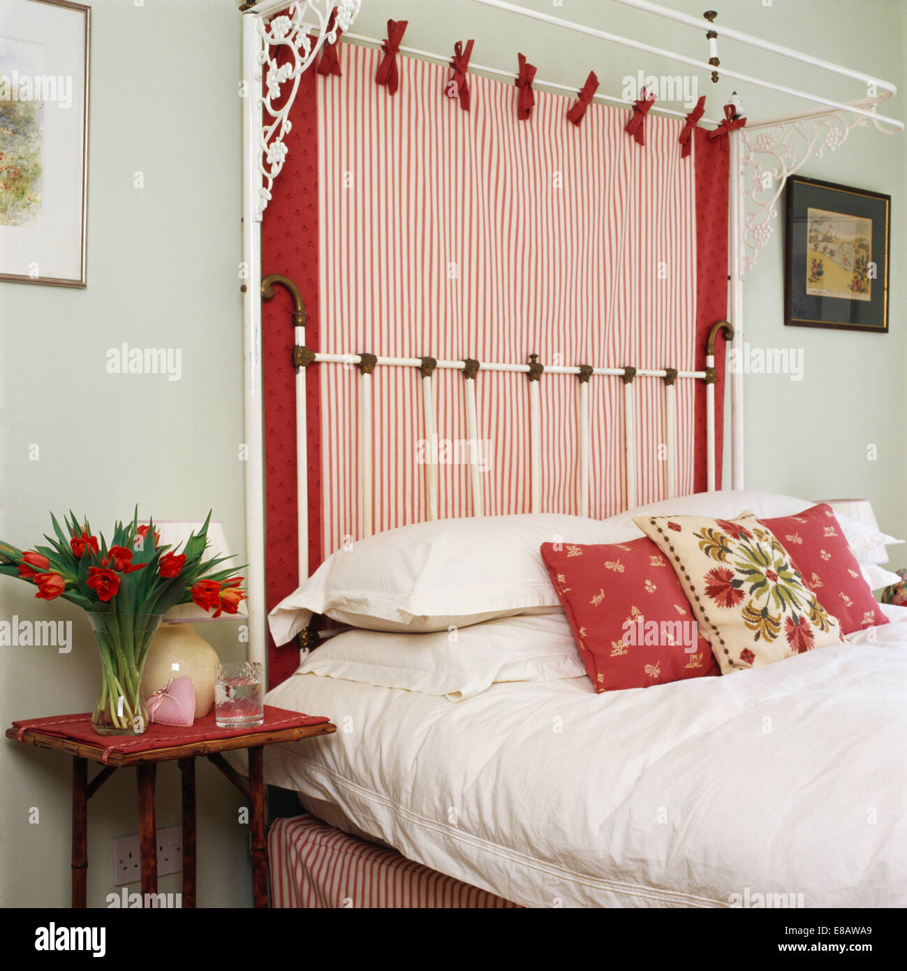 Blasses Grün Schlafzimmer mit rot + weiß gestreiftes Tuch auf halb-Tester Bett mit weißen Kissen und rot gemusterten Kissen Stockfoto