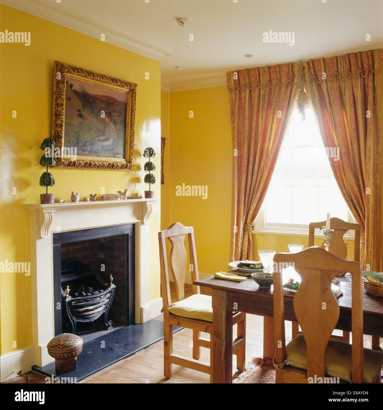 Großen goldgerahmten Spiegel über dem Kamin im gelben Speisesaal mit Full-length Vorhänge am Fenster Stockfoto