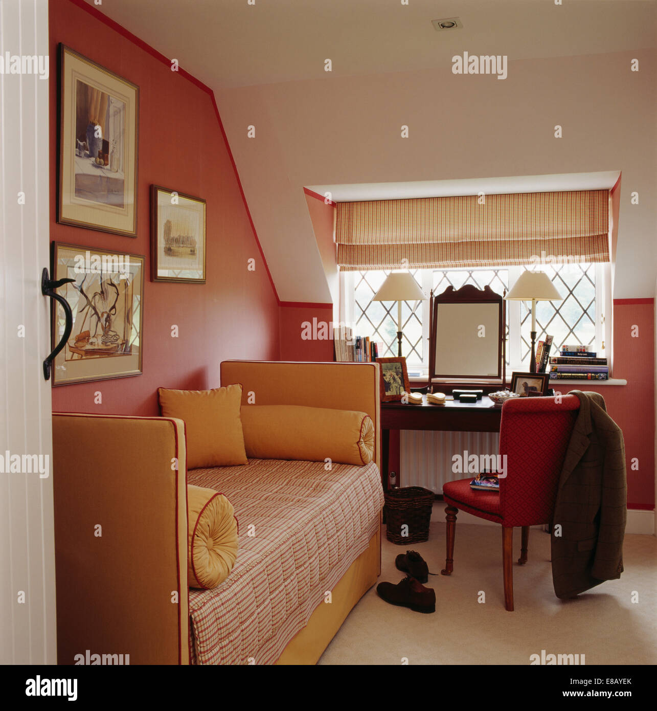 Nackenrolle Kissen auf gemusterte Tagesbett in rosa Gästeschlafzimmer mit gestreiften Rollo am Fenster Stockfoto