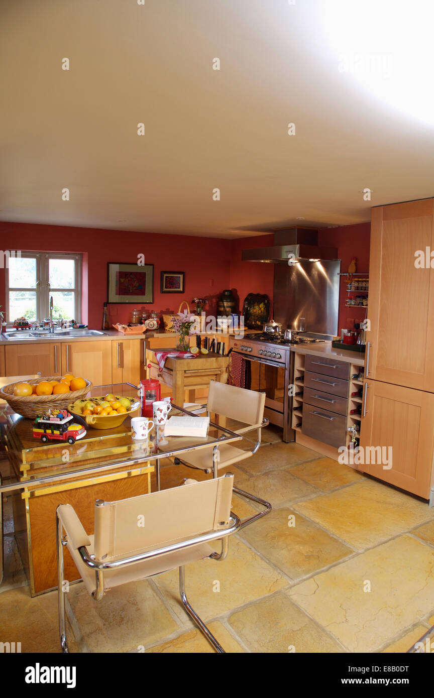 Moderne Beige Lederstühle und Esstisch aus Glas in rot Cottage Küche Erweiterung mit Steinböden Stockfoto