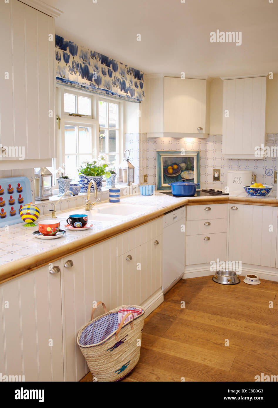 Warenkorb auf Holzboden im Cottage-Küche mit Creme und blau und weiß blind auf Fenster Stockfoto