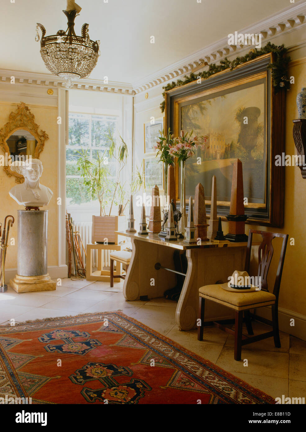 Klassische Büste auf Sockel im Land Halle mit antiken Möbeln und Sammlung von Obelisken auf Tisch unten große Gemälde Stockfoto