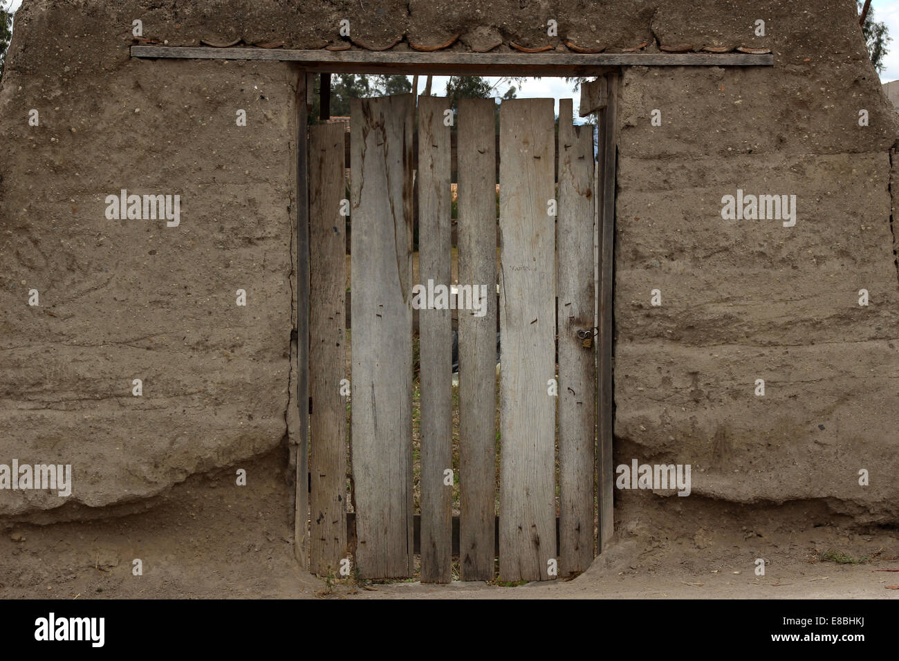 Ein hölzernes Tor inmitten einer Adobe-Mauer auf einem Grundstück in Cotacachi, Ecuador Stockfoto