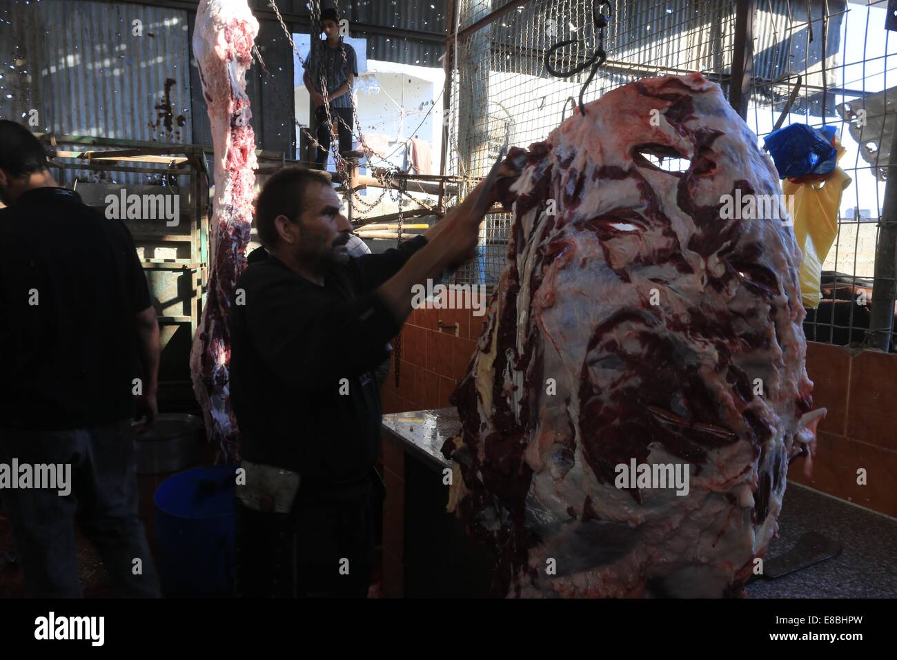 Gaza-Stadt, Gazastreifen, Palästinensische Gebiete. 4. Oktober 2014. Ein palästinensische Metzger schneidet das Fleisch einer Kuh nach der Schlachtung der am ersten Tag des Eid al-Adha oder oder das Fest der Opfer in Gaza-Stadt am 4. Oktober 2014. Muslime auf der ganzen Welt feiern Eid al-Adha, das Festival von Opfern, um das Ende der Pilgerfahrt durch Schlachtung Schafe, Ziegen, Kühe und Kamele um Propheten Abrahams Bereitschaft, seinen Sohn Ismail auf Gottes Befehl Credit Opfern zu gedenken: Mohammed Asad/APA Bilder/ZUMA Draht/Alamy Live News Stockfoto