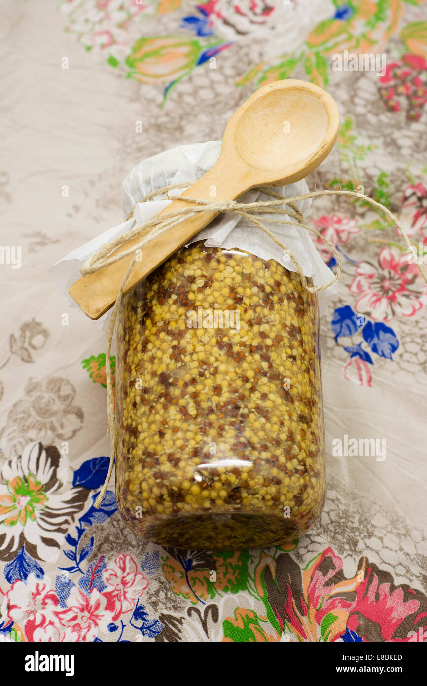 Glasflasche. Senf, klassisch, Bohnen. Blumen Hintergrund, Vintage-Farben Stockfoto