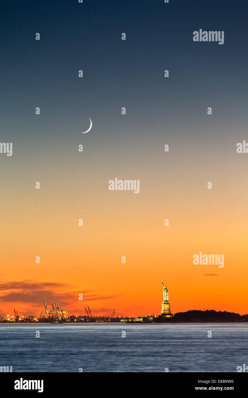 Freiheitsstatue unter einer steigenden Mondsichel bei Sonnenuntergang Stockfoto