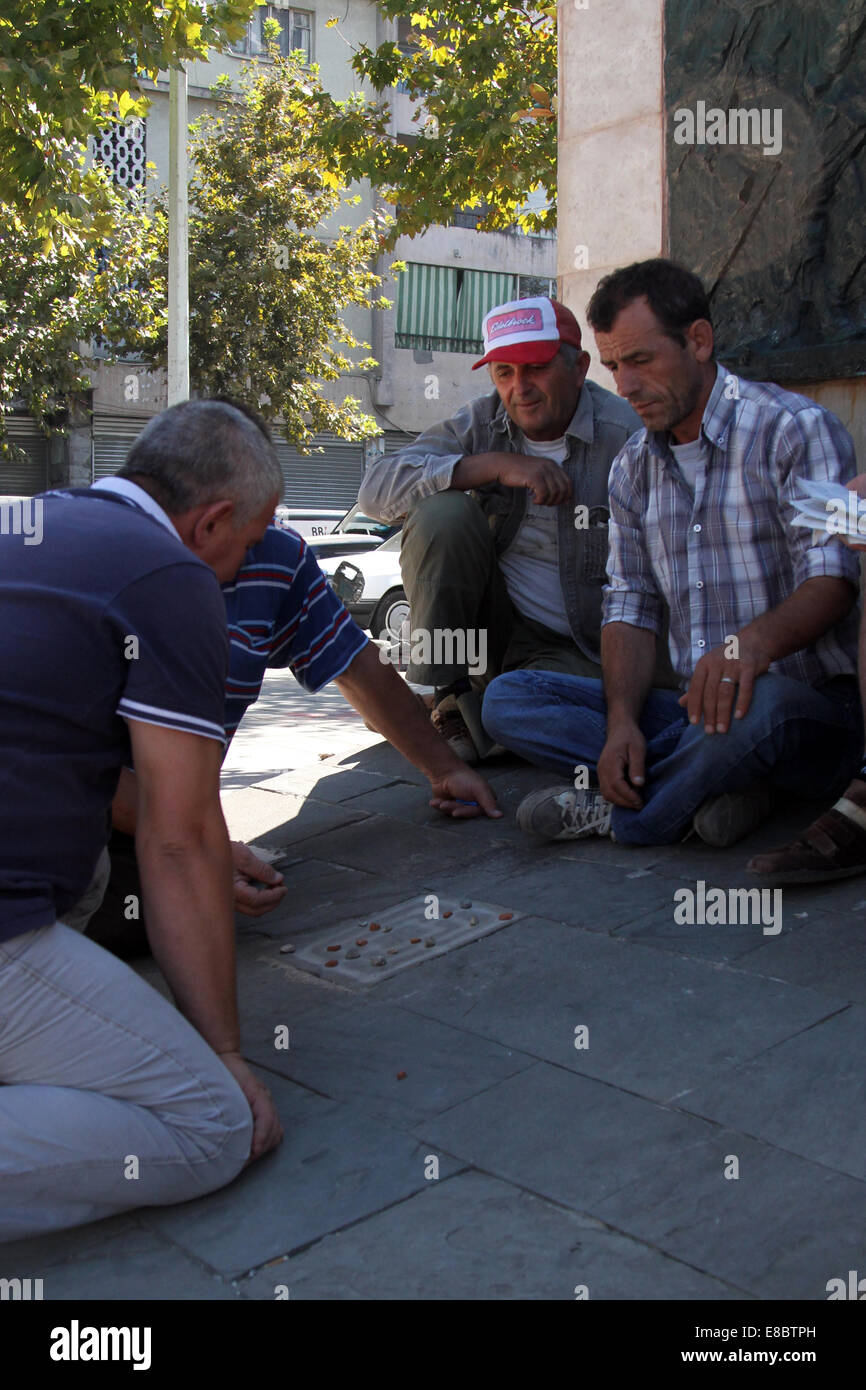 Männer, die ein Spiel von "Titzmitz" im Schatten der Statue zu unbekannten Partisanen in zentralen Tirana, Albanien Stockfoto