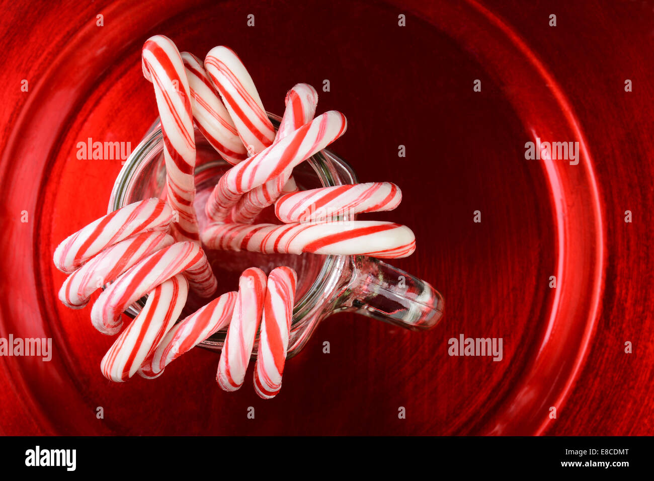 Hohen Winkel Schuss aus einer Gruppe von Weihnachten candy Canes in einem Einmachglas auf einer roten Platte. Stockfoto