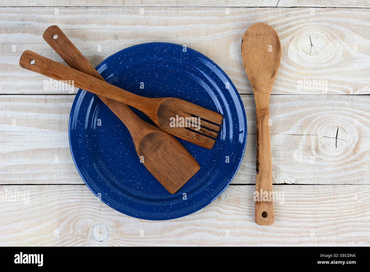Hohen Winkel Schuss einer blau gesprenkelt Platte mit Holzutensilien auf einem rustikalen Bauernhaus Stil Küchentisch. Stockfoto