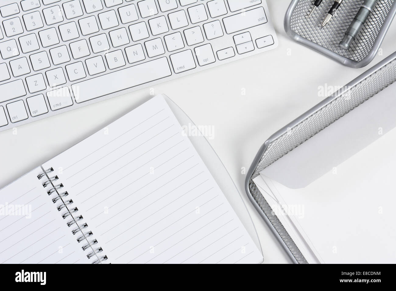 Hohen Winkel Schuss aus einem weißen Schreibtisch mit vorwiegend weißer und silberner Office-Objekte. Elemente enthalten, Tastatur, Pad, Stifte, Kompass, und Stockfoto