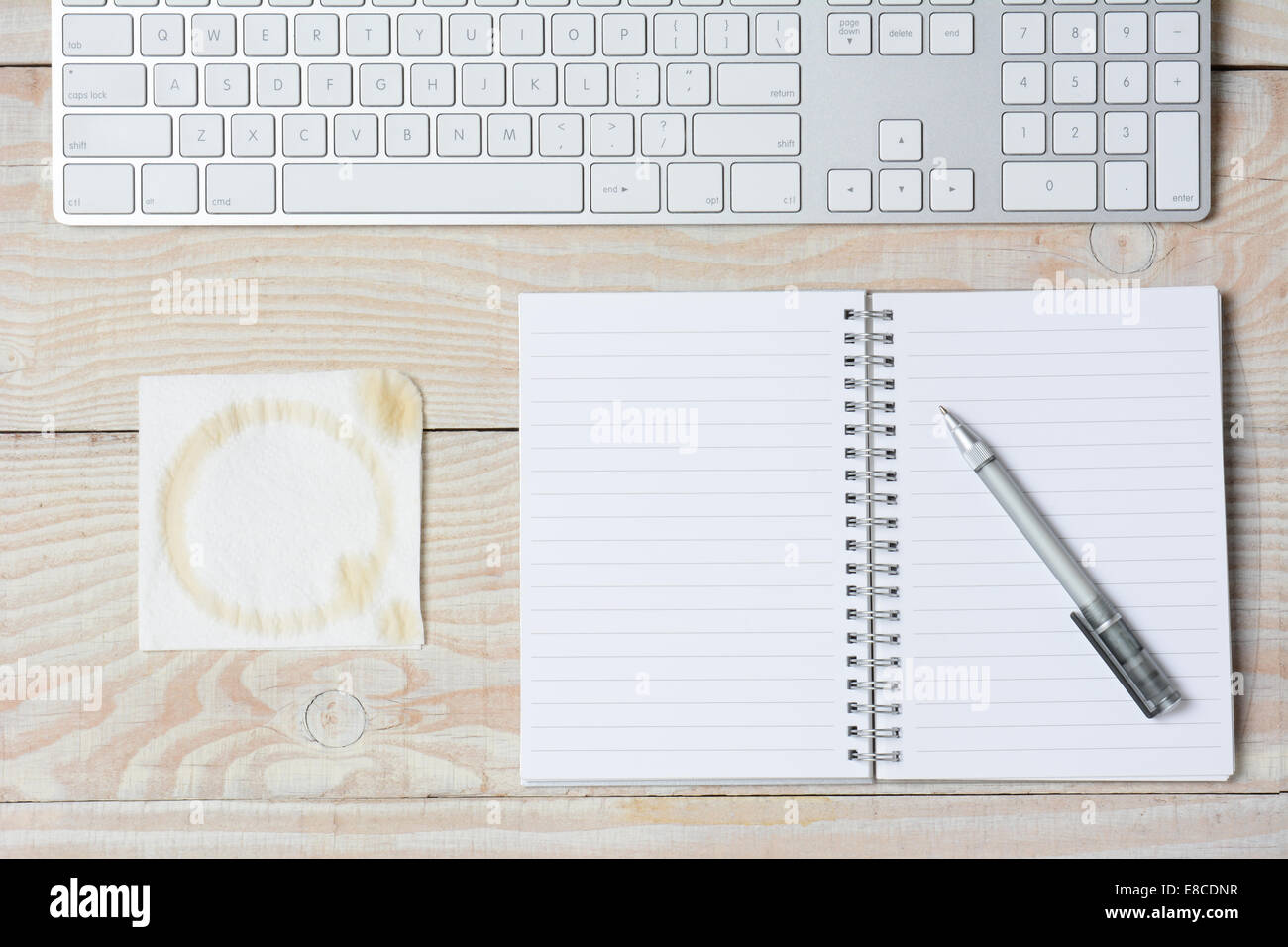 Hohen Winkel Schuss aus einem weißen rustikalen Schreibtisch mit modernen Tastatur, Notebook und Serviette mit einem Kaffeefleck. Querformat. Stockfoto