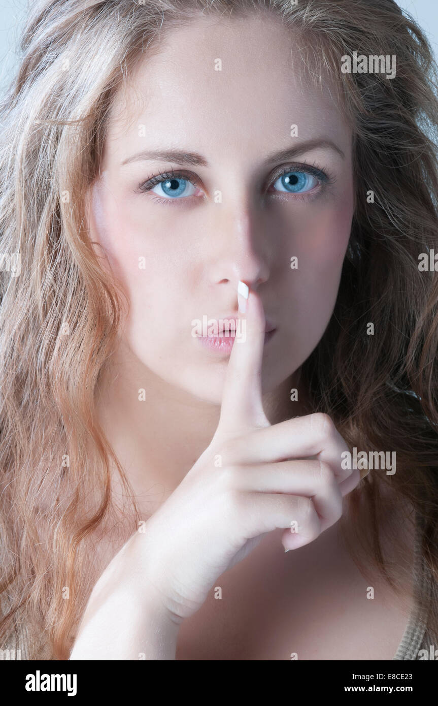 Schöne junge Frau mit der hand über den Mund in eine stille Geste Stockfoto