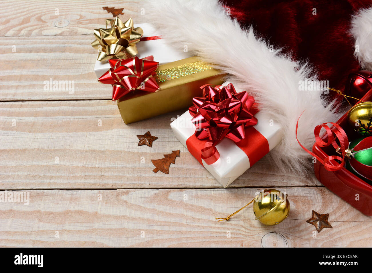 Hohen Winkel Nahaufnahme Weihnachtsgeschenke und Santa Claus Hut auf einem rustikalen weißer Holztisch. Querformat mit Textfreiraum. Stockfoto