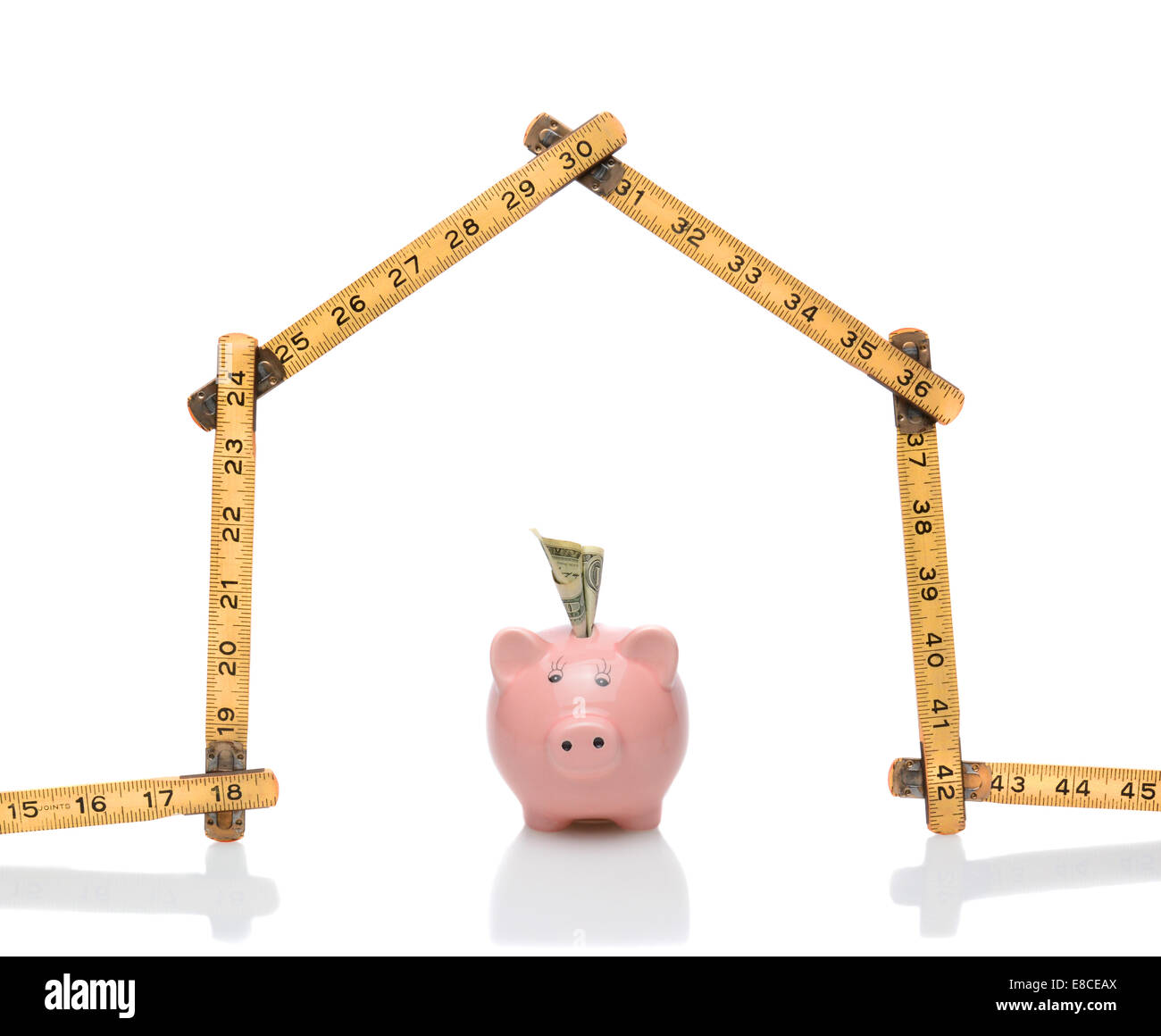 Ein Tischler Herrscher in der Form eines Hauses mit einem Sparschwein unter dem Dach. Querformat auf weiß mit Reflexionen. Wunderbar Stockfoto