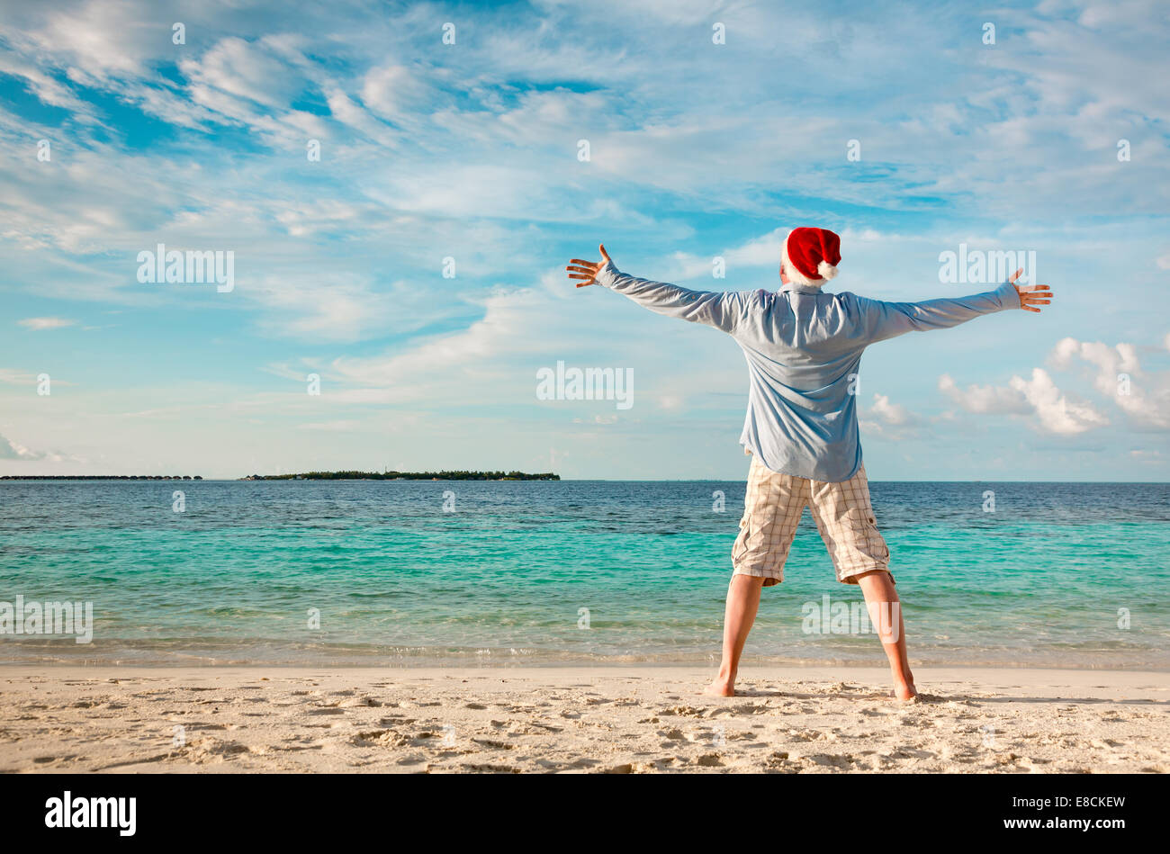 Weihnachtsferien - Mann in Nikolausmütze am tropischen Strand Stockfoto