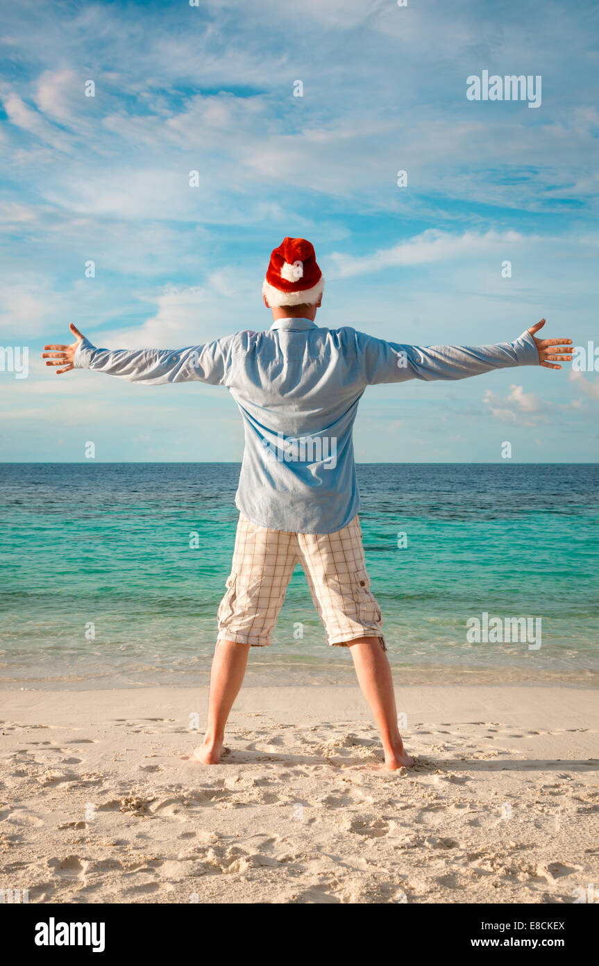 Weihnachtsferien - Mann in Nikolausmütze am tropischen Strand Stockfoto