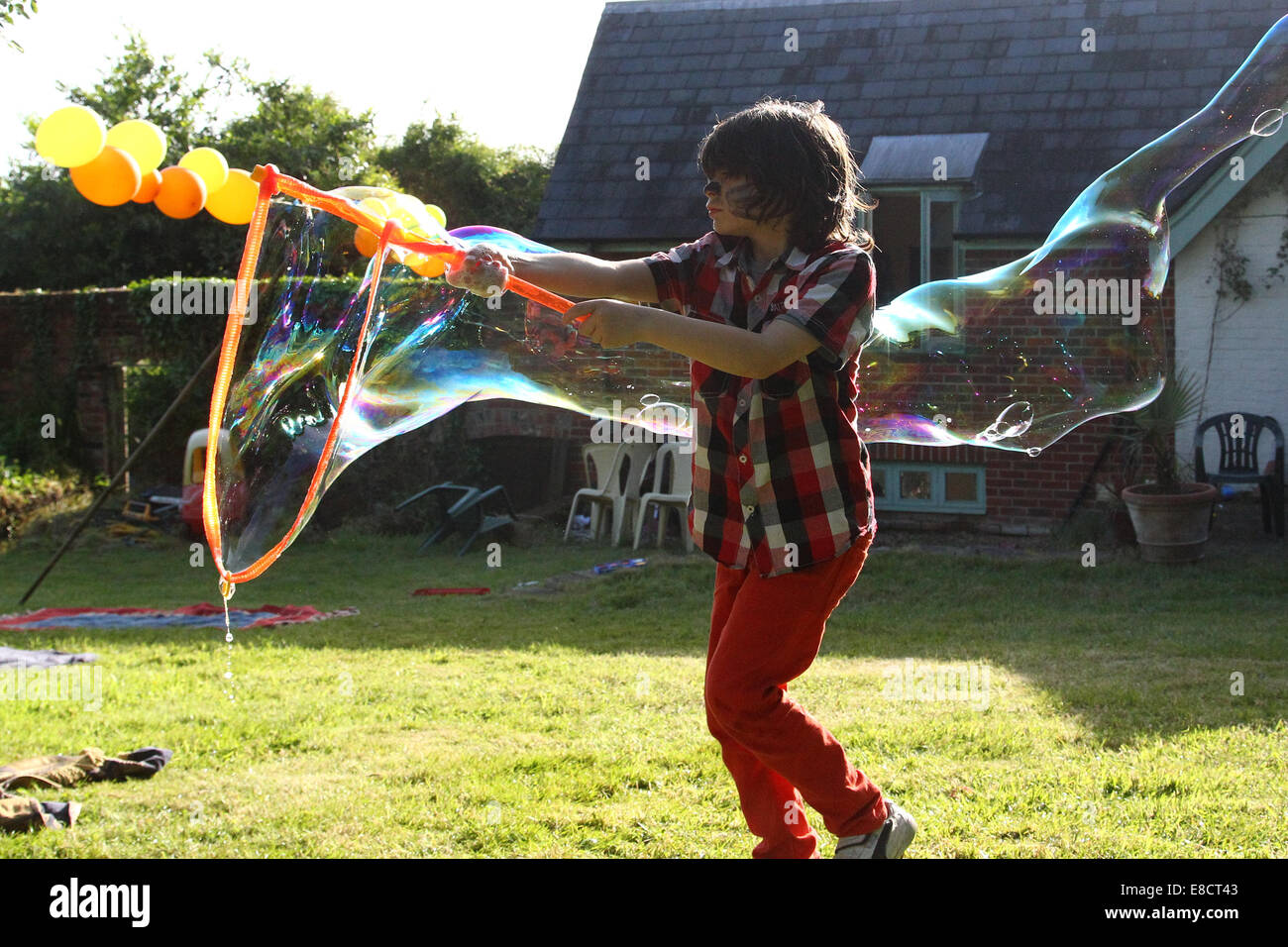 Ein kleines Kind, dass Luftblasen in einem Garten an einem Sommertag während einer Gartenparty. Stockfoto