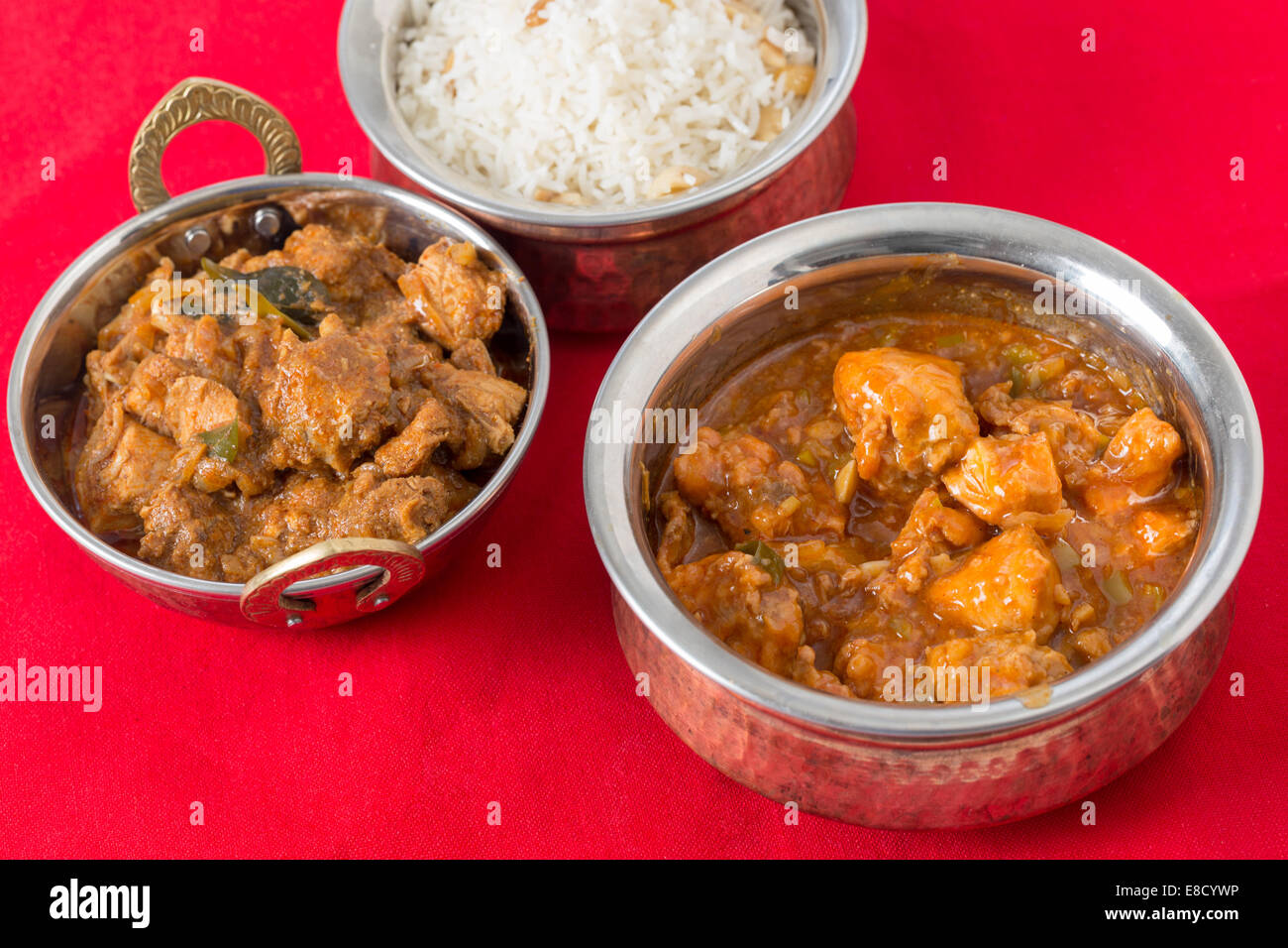 Chili-Knoblauch-Huhn und Malabar chicken Curry mit Cashew Reis auf einer roten Tischdecke. Stockfoto