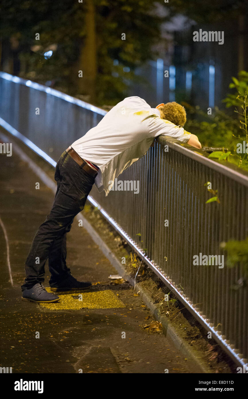 Eine betrunkene Jugend lehnt sich über Geländer nach einer durchzechten Nacht schwere Alkoholexzesse in Cardiff, Wales. Stockfoto